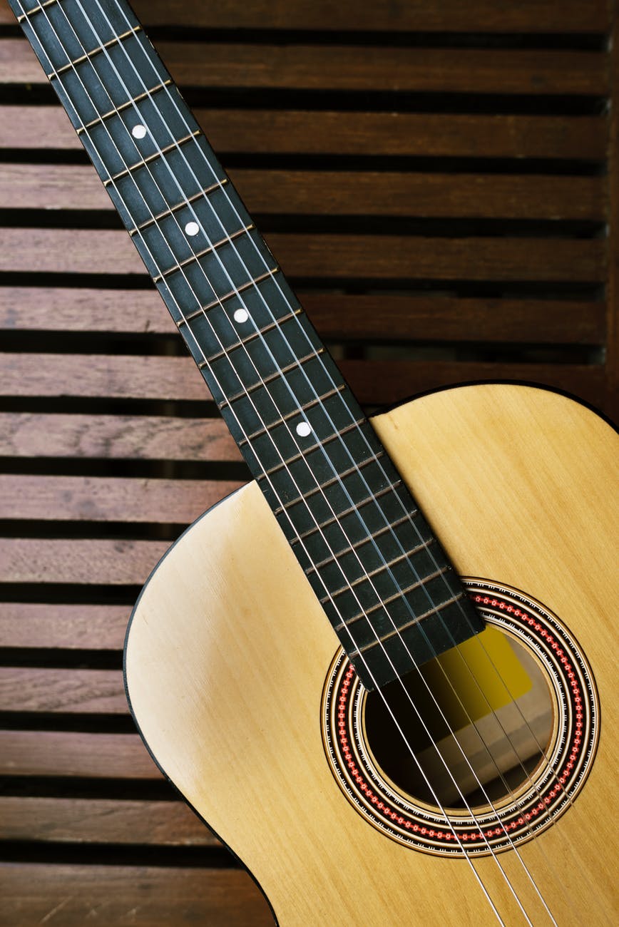 brown acoustic guitar on brown wooden board